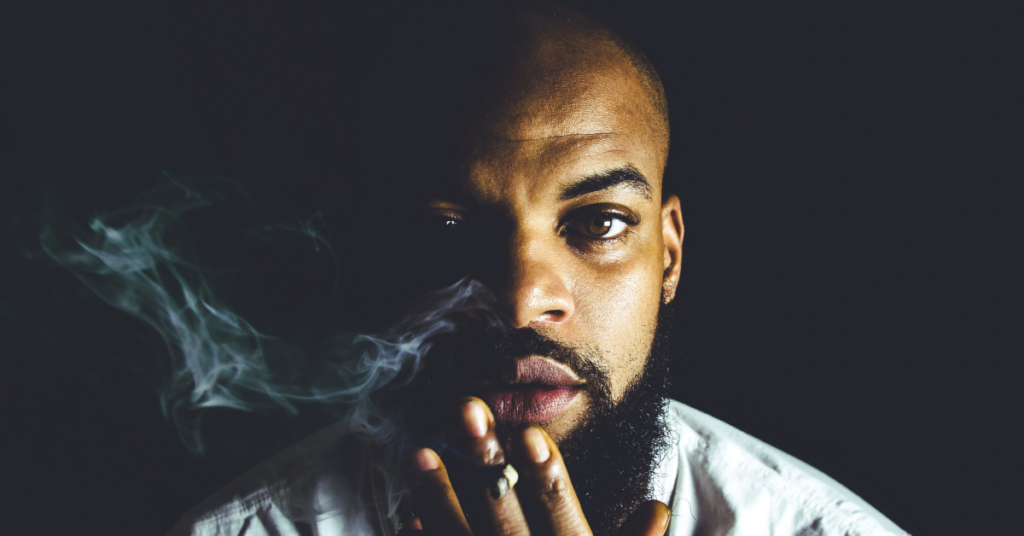 a black man holding a cigarette